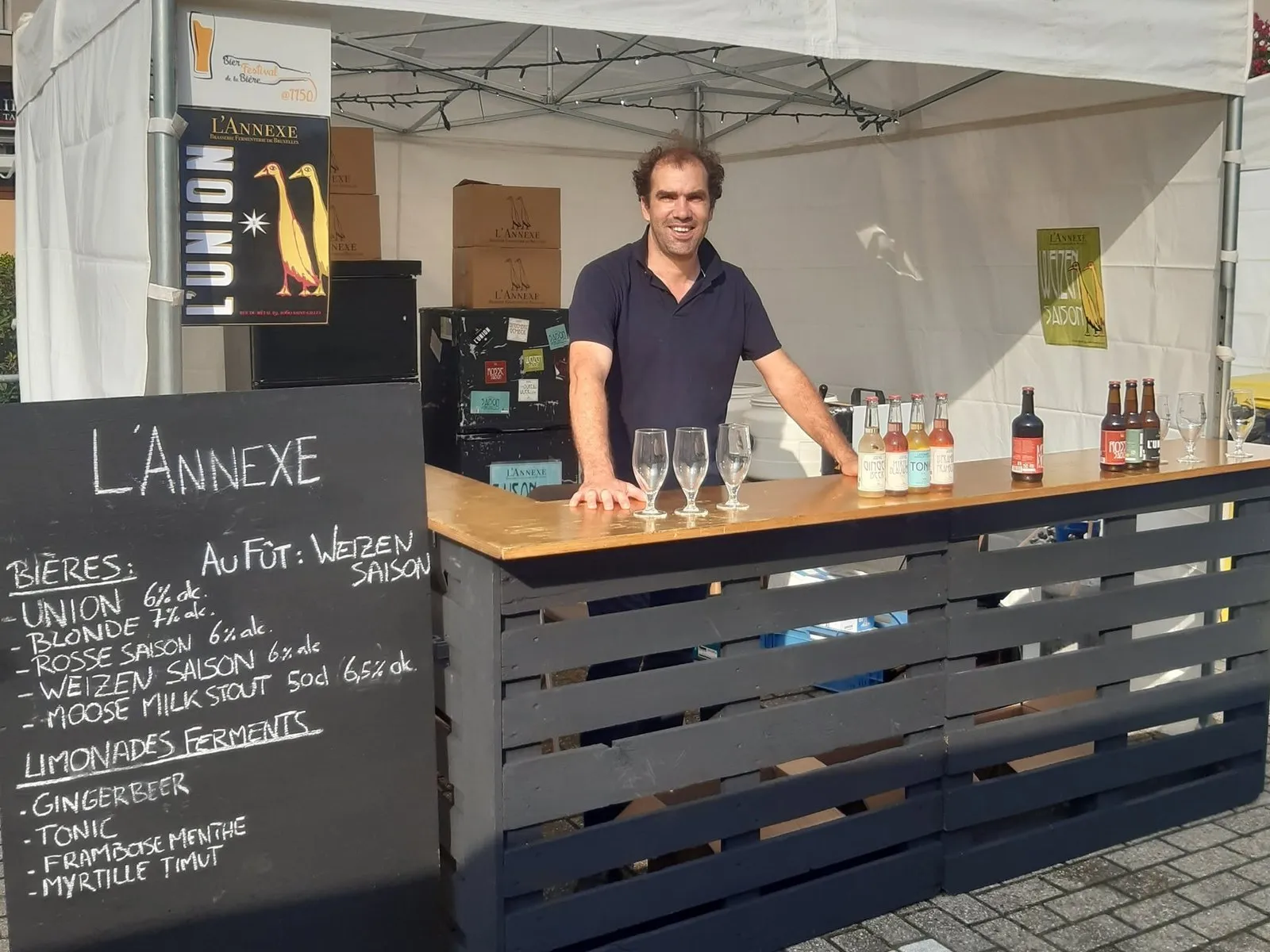 De stand van L'Annexe, met het krijtbord en de flessen bier en limonade op de toog