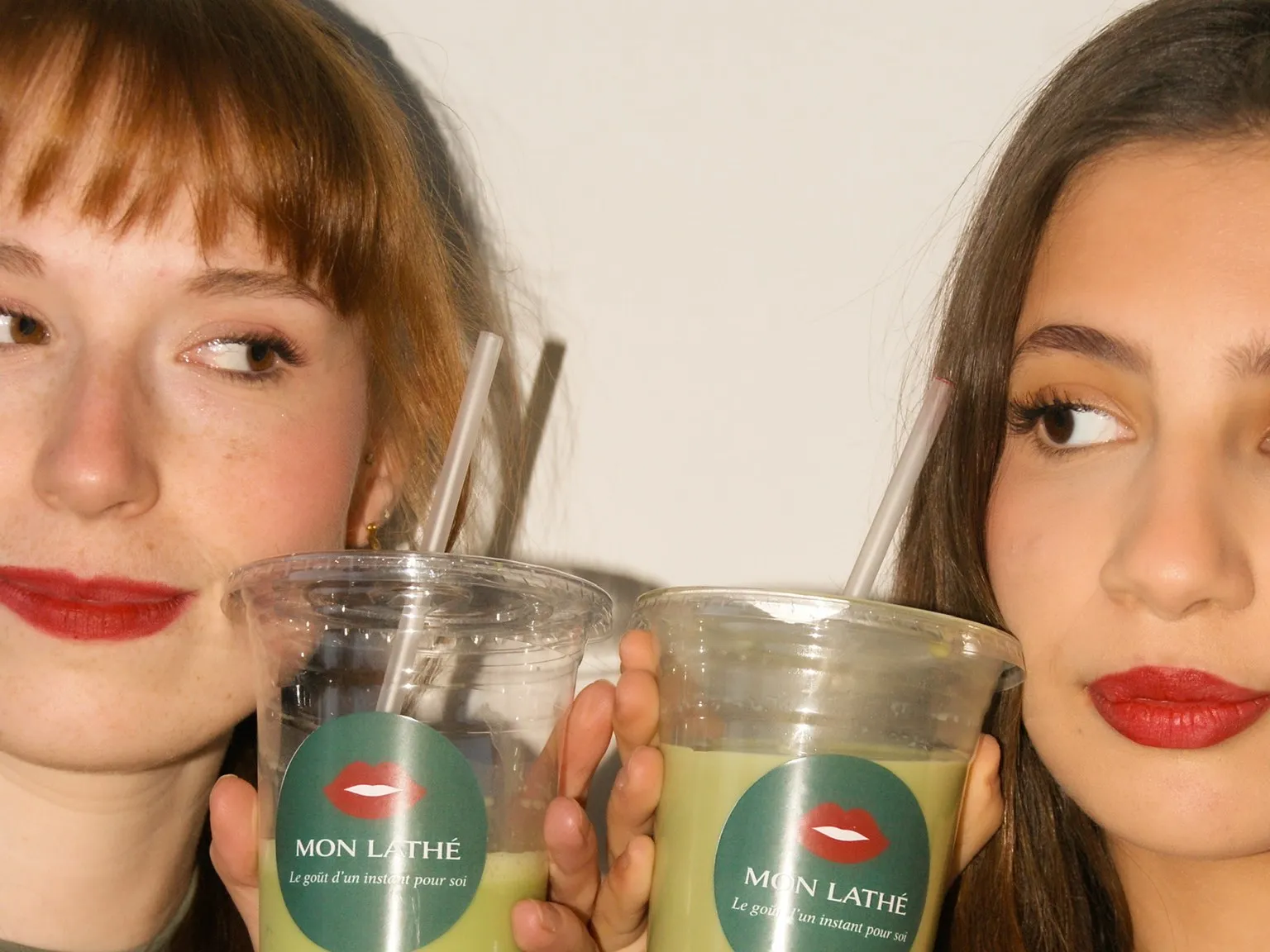 Two young women raising their Mon Lathé cups of iced matcha