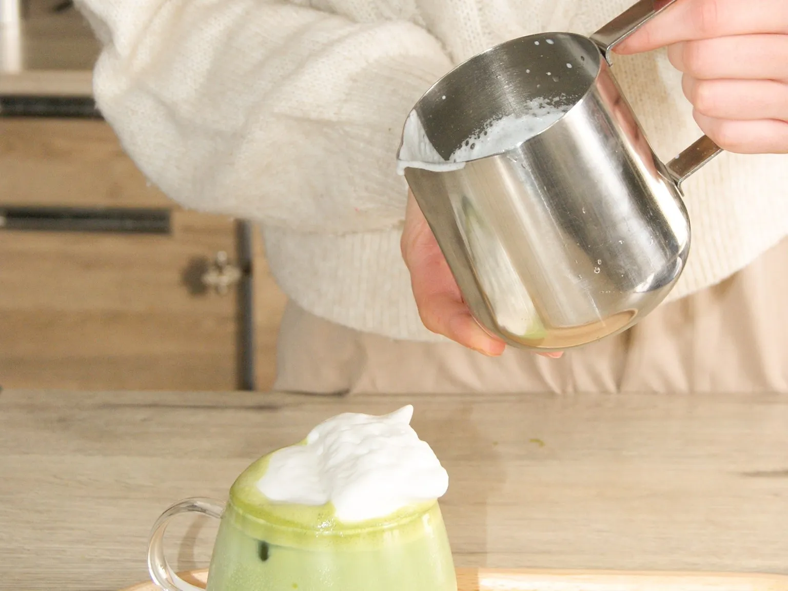 Le lait moussé prêt à être versé sur un matcha latte, un sachet Mon Lathé posé à côté