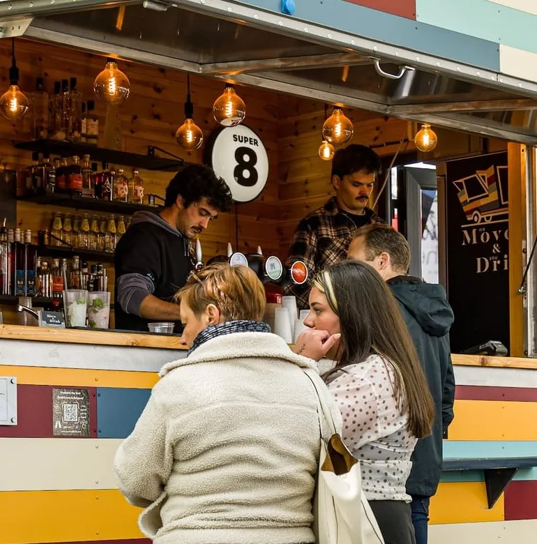 Deux barmen au comptoir du bar Move & Drink, éclairé par des ampoules