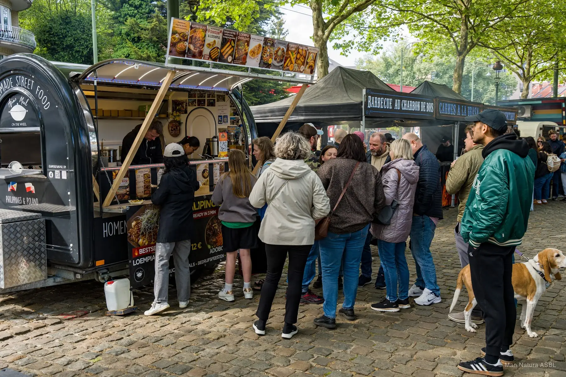 File d'attente devant un food truck de wraps sur les pavés, un chien accompagne les visiteurs