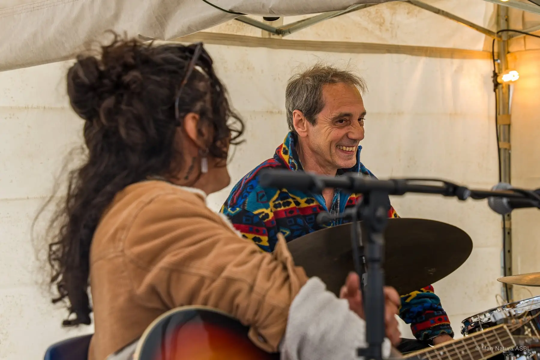 Deux musiciens échangent un sourire pendant leur concert sous la tente