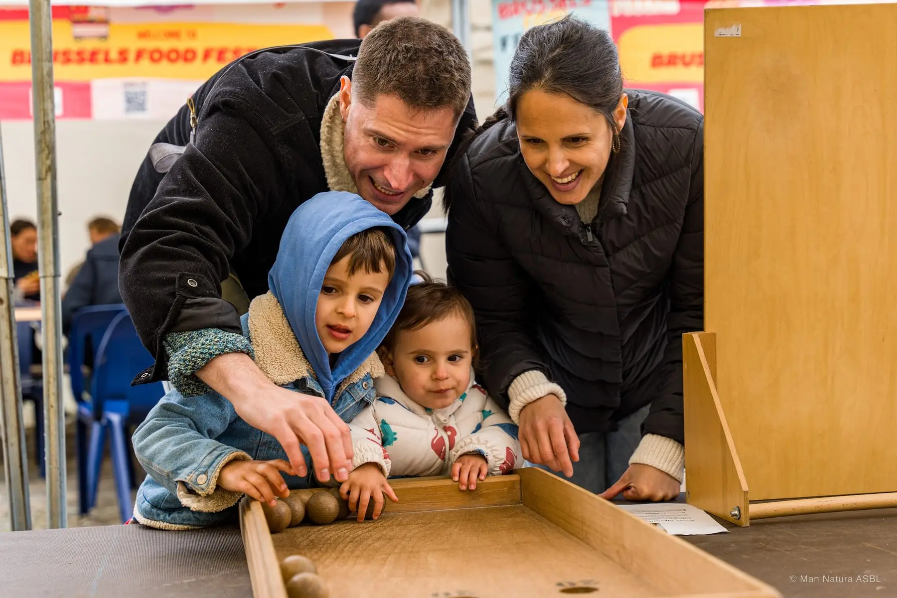 Une famille joue avec ses deux jeunes enfants au Kids corner du festival