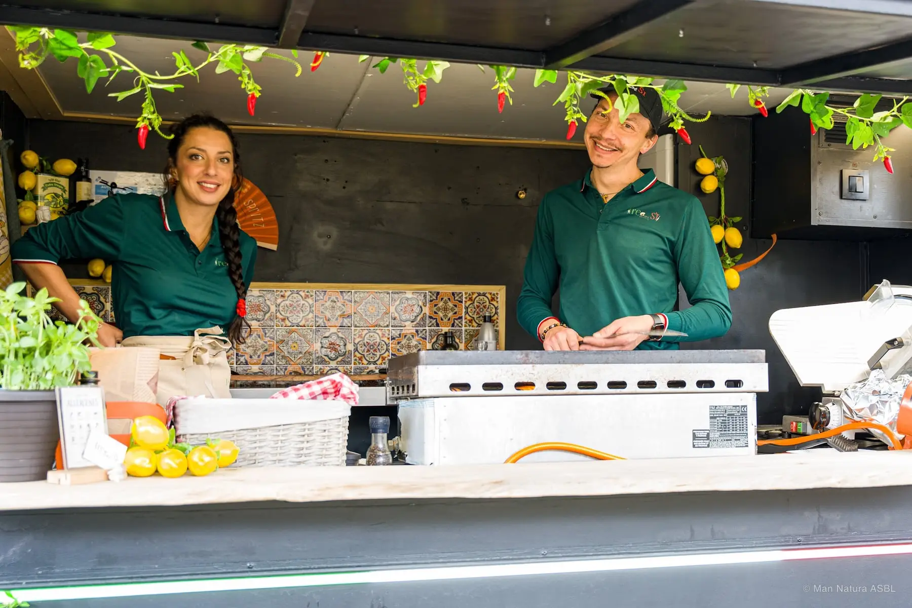 Deux vendeurs en polo vert accueillent les clients dans leur camion décoré de piments et citrons