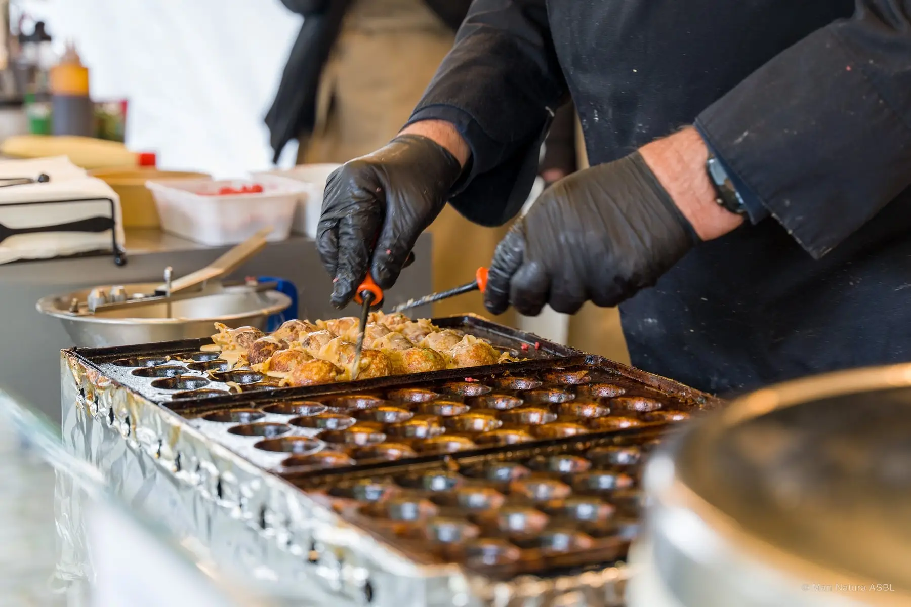 Préparation de takoyaki : les boules de pâte sont retournées une à une dans la plaque en fonte
