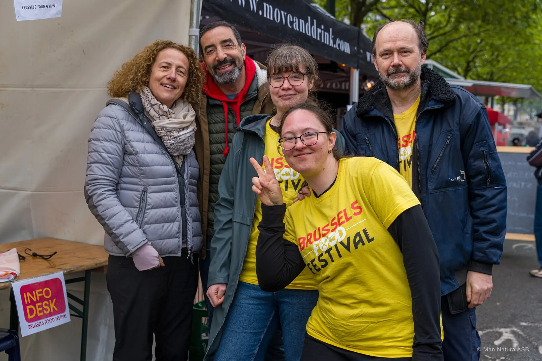 L'équipe du festival en t-shirt jaune pose avec des visiteurs devant l'info desk