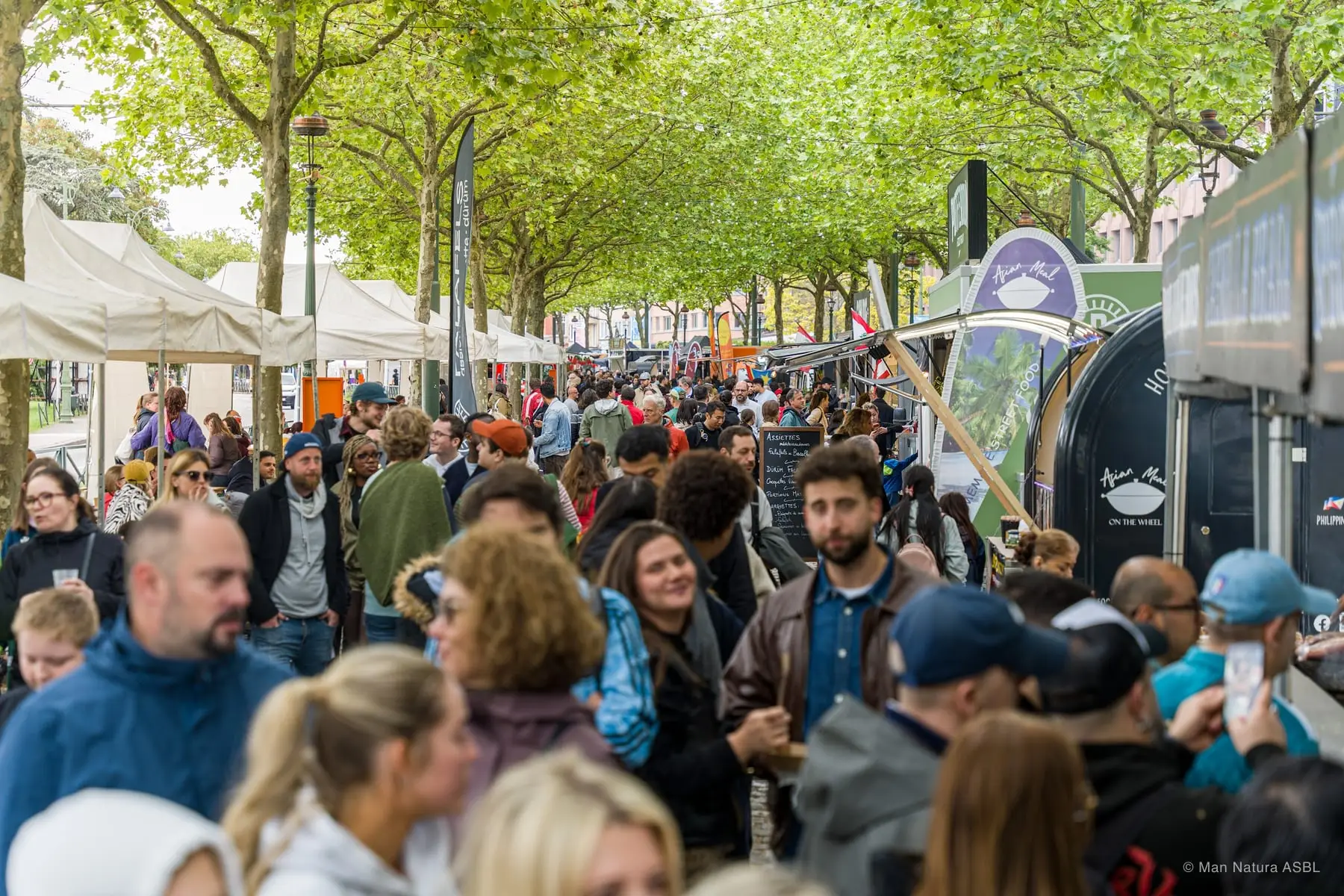 L'allée noire de monde entre les stands, un après-midi de festival