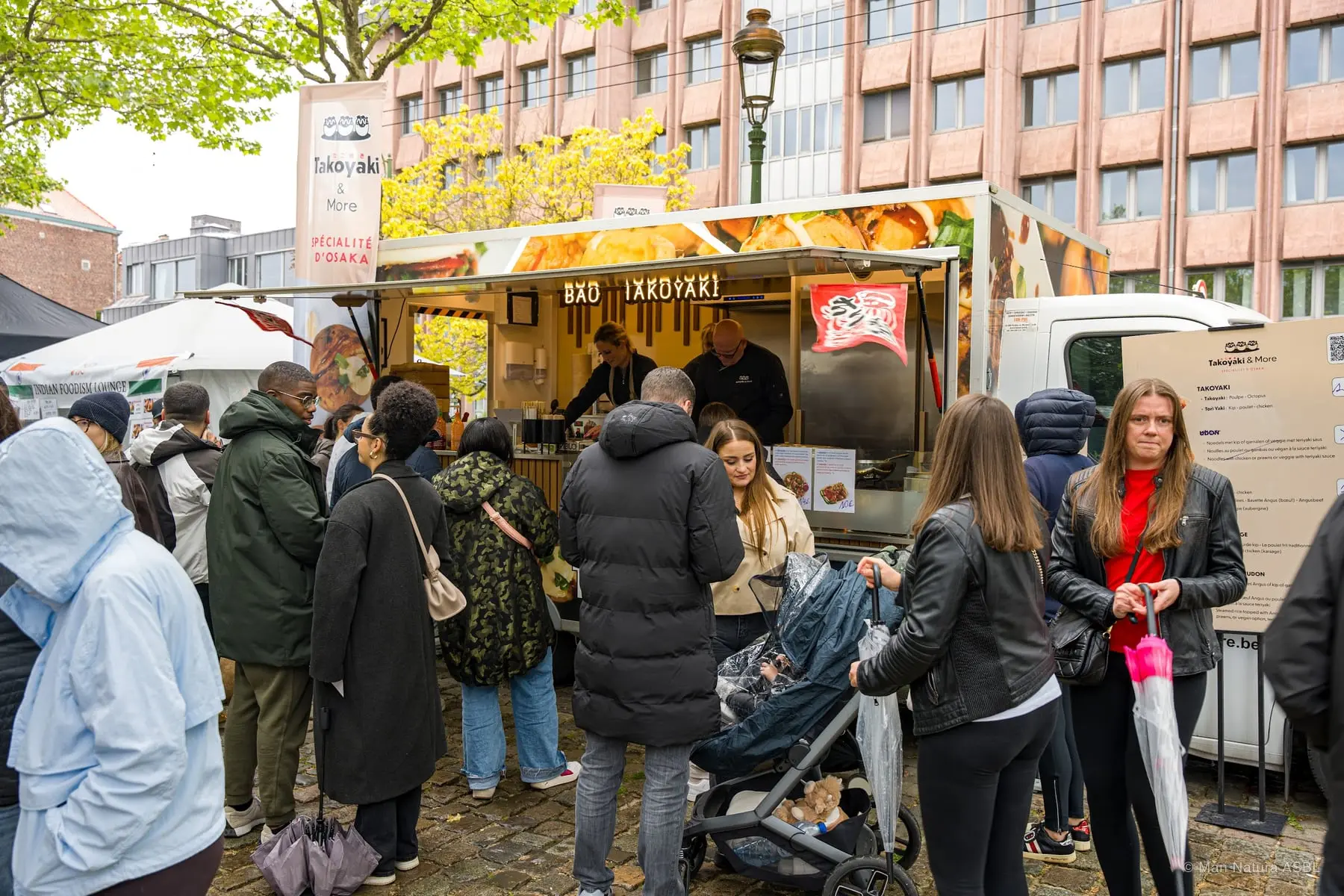 File d'attente devant le stand de takoyaki, façades bruxelloises à l'arrière-plan
