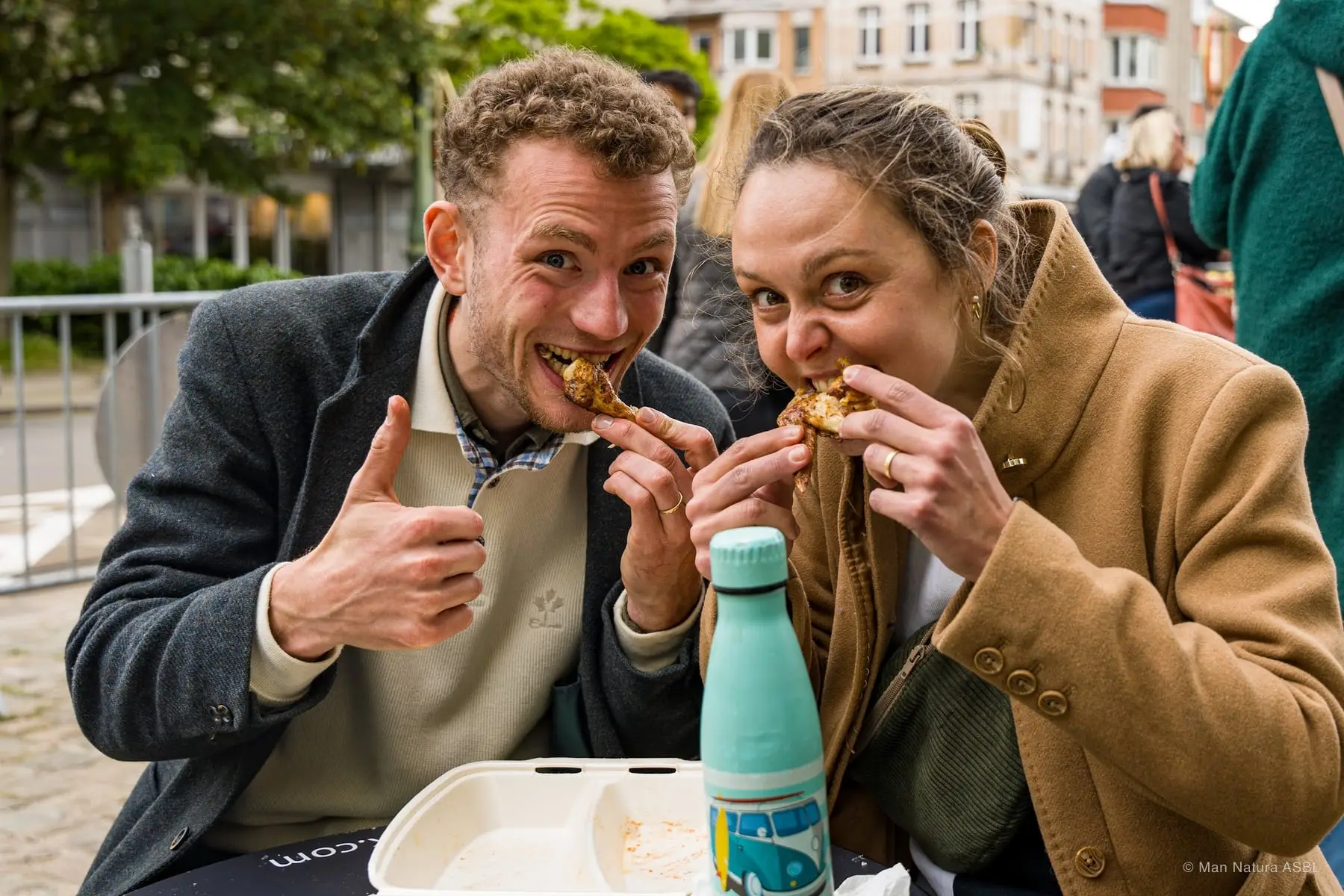 Un couple croque en même temps dans ses parts, attablé au festival