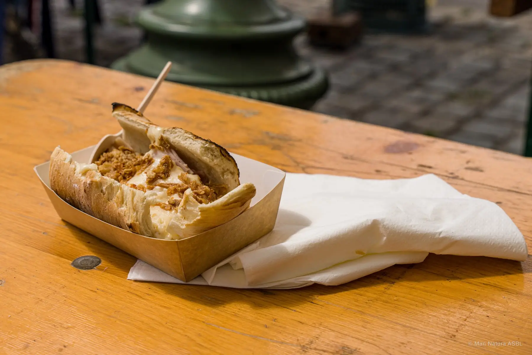 Sandwich effiloché servi dans sa barquette en carton sur une table en bois