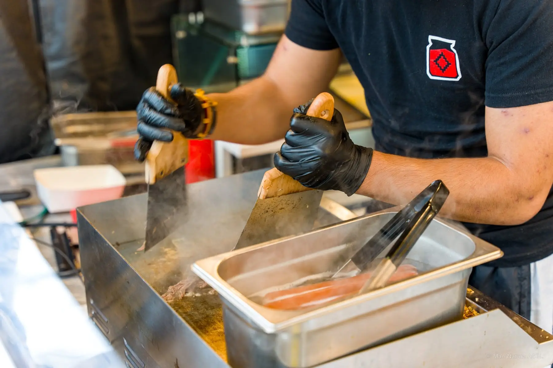 Un cuisinier dresse une assiette à la spatule au-dessus de son bac