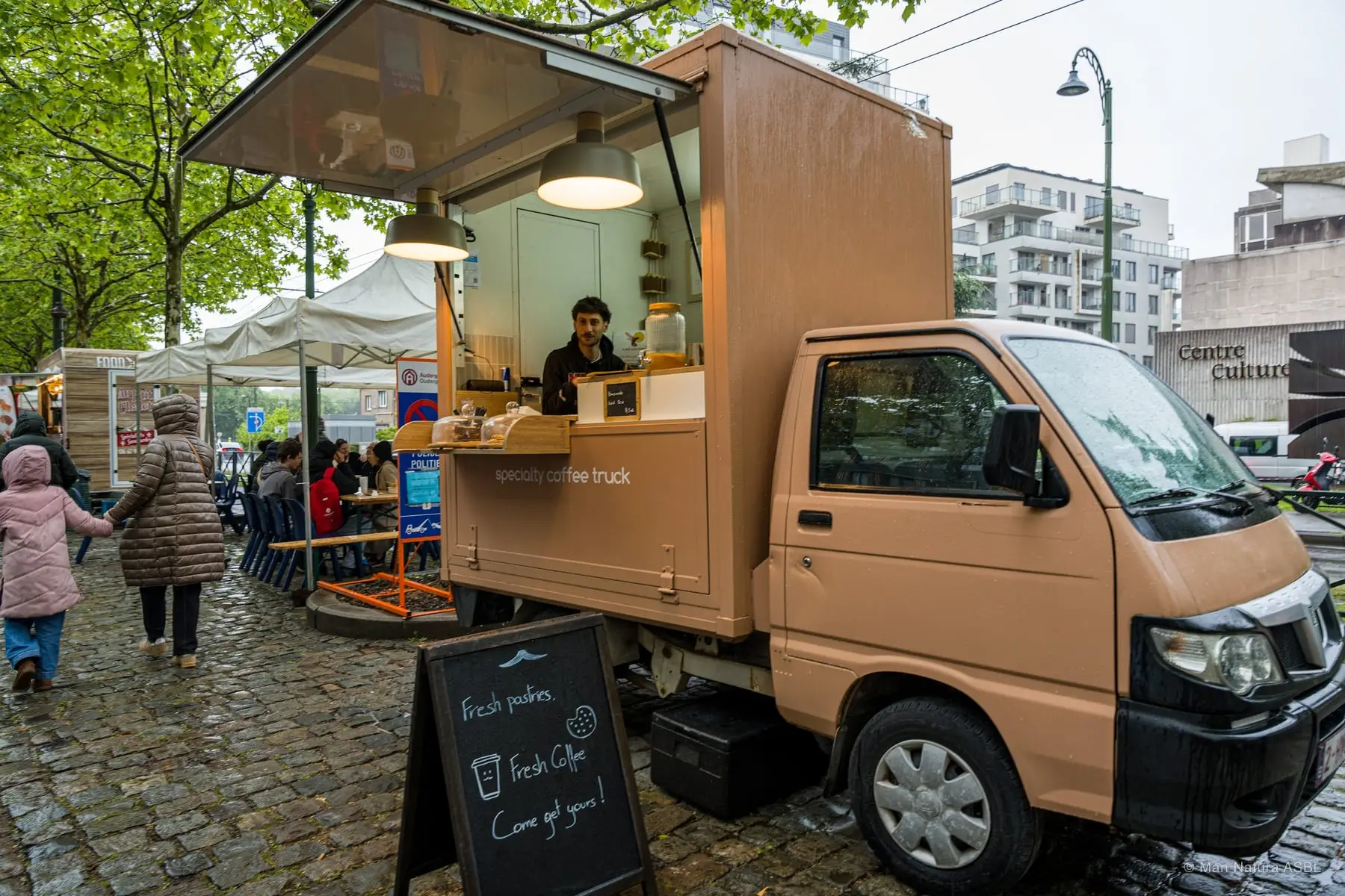 Petit camion-café en bois garé sur les pavés, ardoise Fresh coffee devant