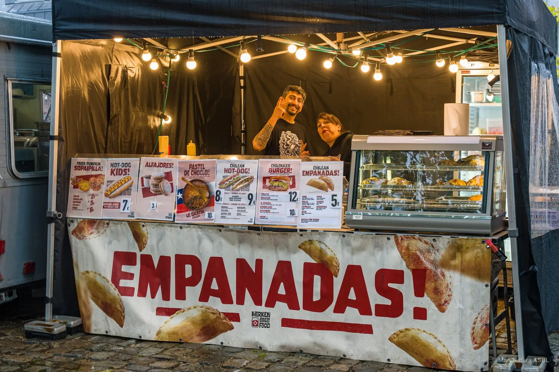 Le stand Empanadas illuminé le soir, deux vendeurs derrière le comptoir